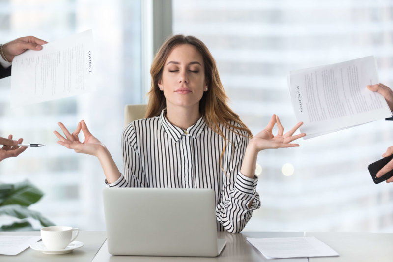 Calm female executive meditating taking break at work for mental balance, mindful businesswoman feeling relief and no stress doing yoga at work ignoring avoiding stressful job and paperwork in office, knowing what her biggest challenges associated with HR Management software are